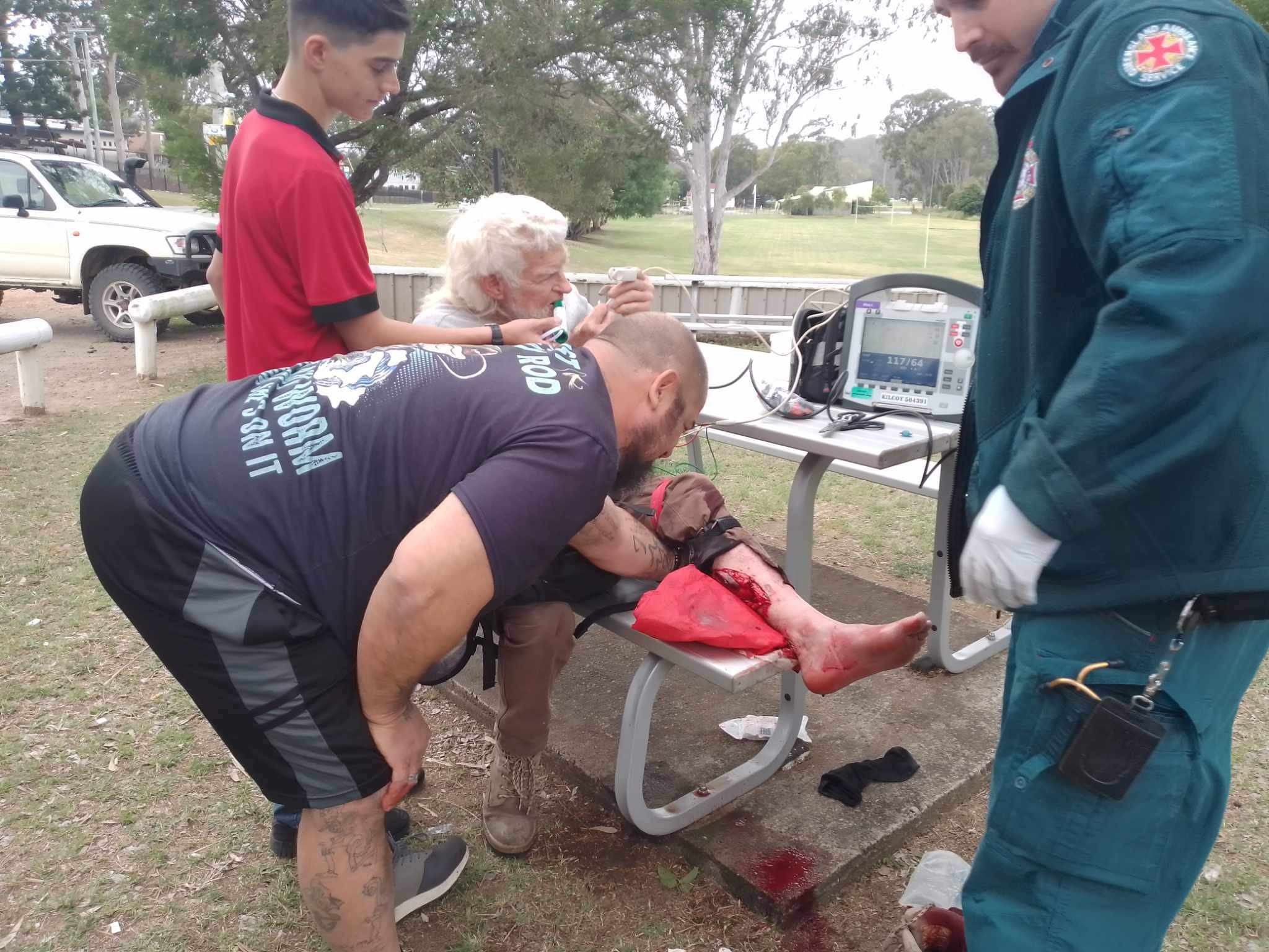 Seth holding a pain reliever for Ed Gordon while paramedics treat the wound.