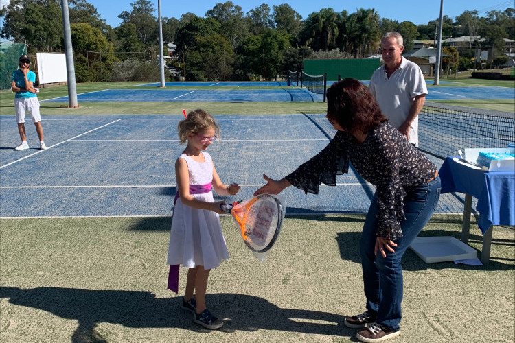 Somerset councillor Cheryl Gaedtke hands over a Wilson tennis racquet to Daisy Oakroot for the lucky door prize, while Kilcoy Tennis Club president Gil Todd looks on.