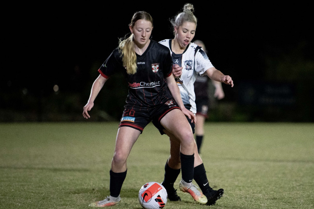 Caboolture Sports FC’s Kayla Carlow tries to maintain possession as an Ipswich opponent comes from behind, during Caboolture Sports FC’s 4-0 win in the senior women’s soccer match at Moreton Bay Central Sports Complex. Photo courtesy of Atnc Photography.