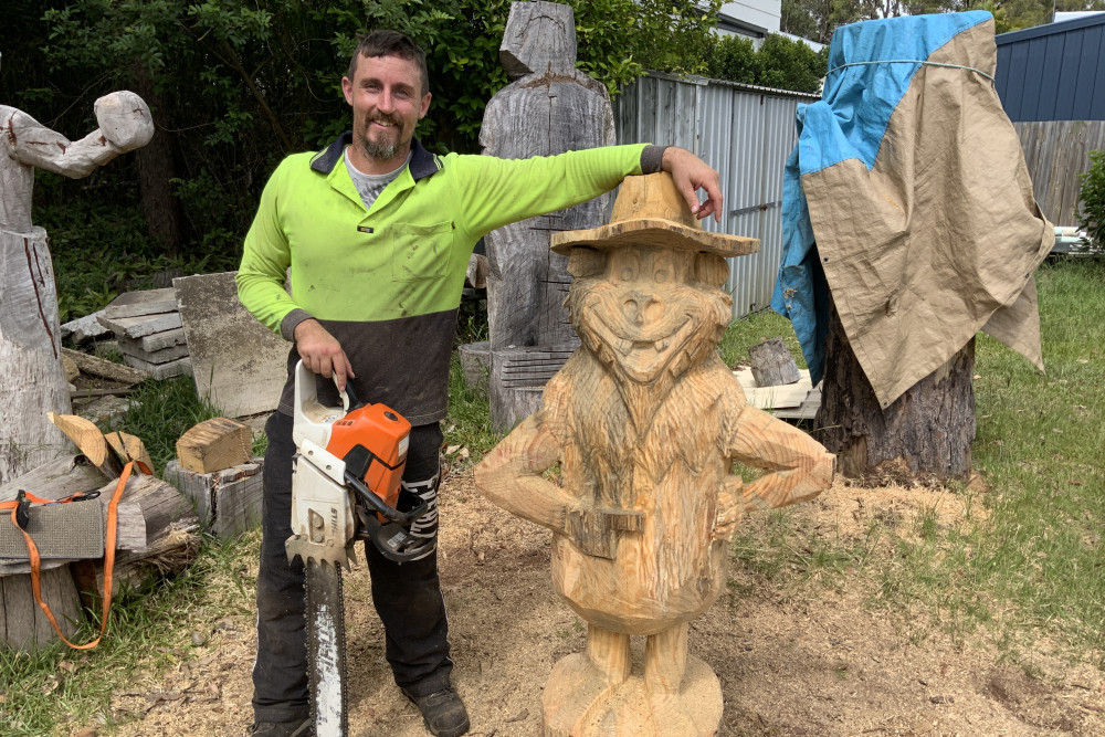 Chainsaw artist Luke Sheehan with the yowie he carved for the Advancetown Hotel Motel. On his agenda now is a sculpture of country musician Chad Morgan.