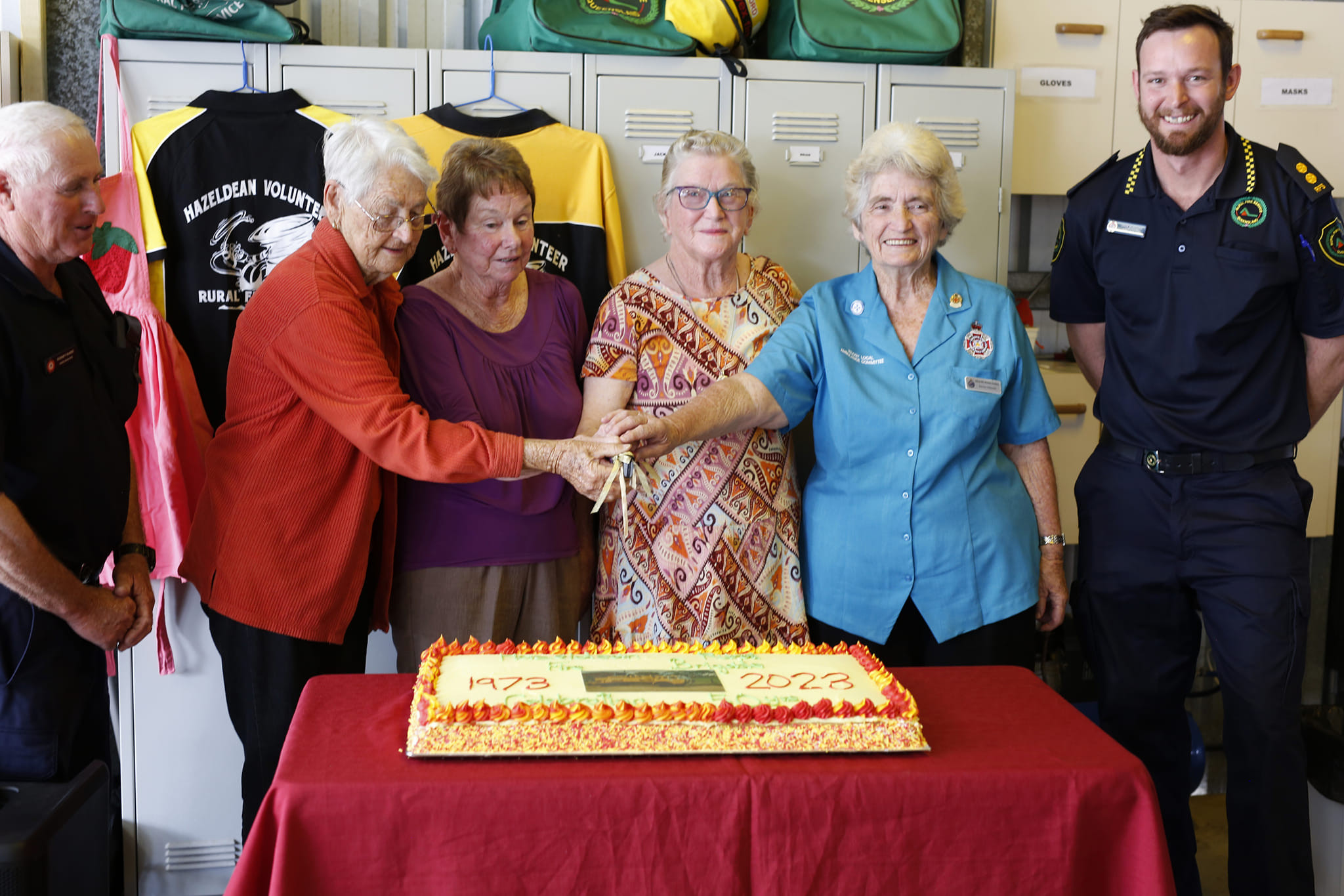 Firefighter widows Grace Carseldine, Lesley Scott, Desley Cobbin and Zandra Hollworth cut the cake, accompanied by Rodney Kunde (far left) and Jack Burford (far right).