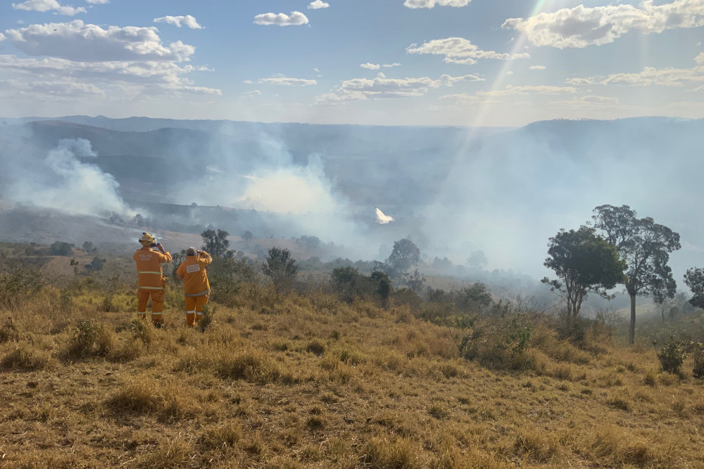 Rural Fire Brigade firefighters watch as a waterbombing aircraft douses one of the Gregors Creek fires