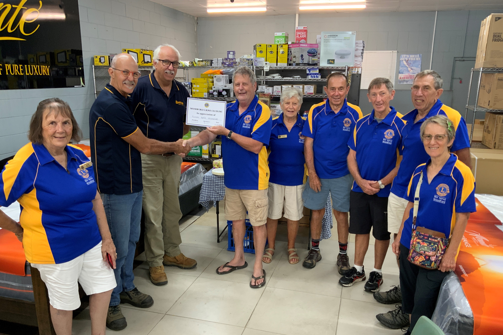 Woodford Lions Club president David Kearns hands a certificate to Blacks Betta Home Living owners Barry and Jeff Black, with other Woodford Lions members in attendance.